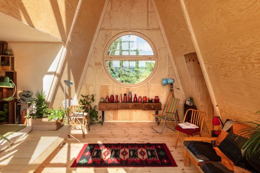 wood cabin with round window, red rug and minimal furniture