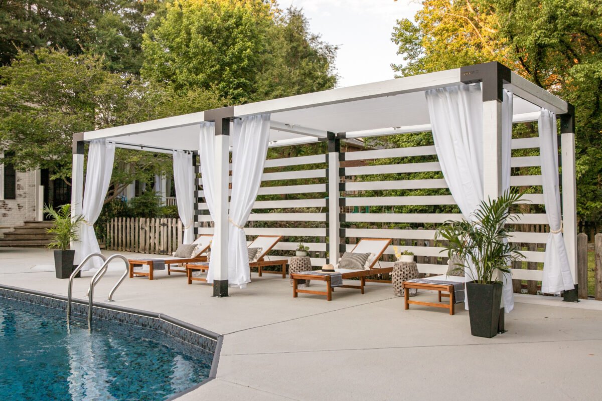 white DIY pergola cabana with outdoor curtains and lounge chairs