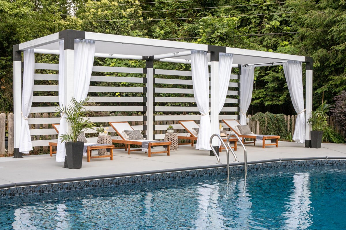 white DIY pergola cabana with outdoor curtains and lounge chairs