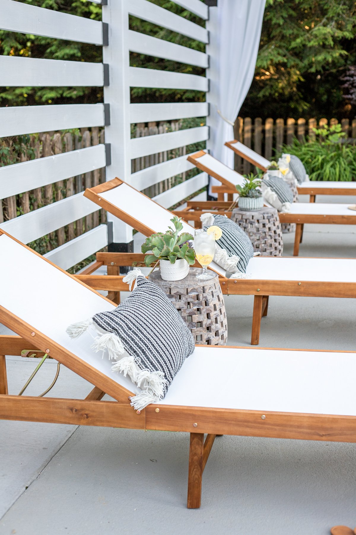 outdoor lounge chairs under white pergola with outdoor curtains and pillows