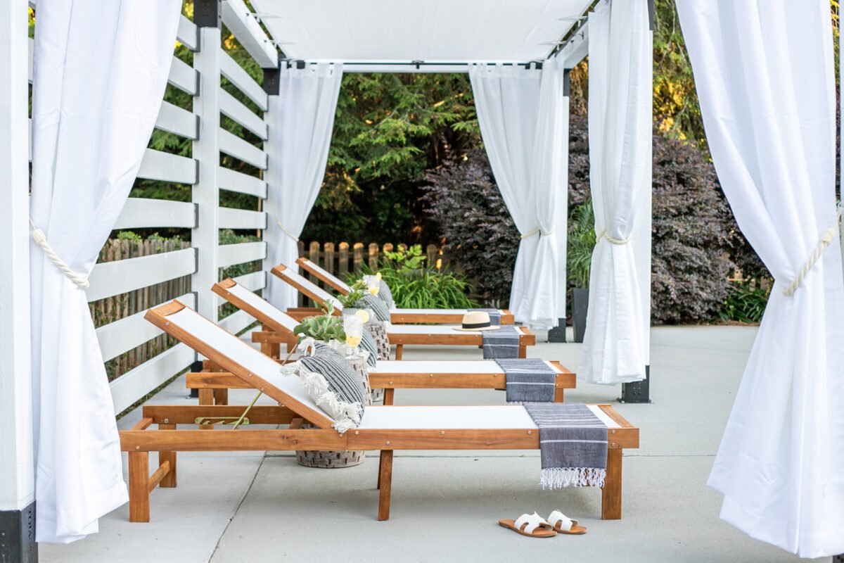 white DIY pergola cabana with outdoor curtains and lounge chairs